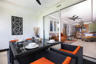a living room with a glass table and orange chairs at Kata Beach Luxury Condo - Spacious - Exquisitely Furnished - 6min walk to beach - 2025 Booking Traveller Award Winner in Kata Beach
