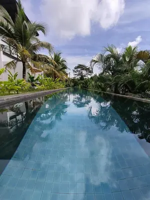 a large swimming pool with palm trees in the background at Sky Lofts Phuket 2 in Thalang