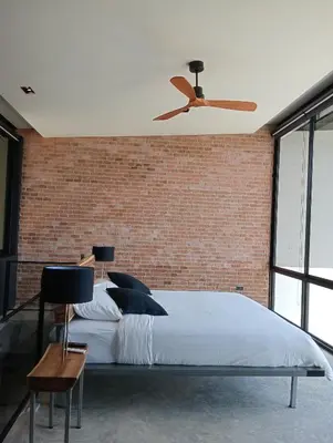 a bedroom with a bed and a brick wall at Sky Lofts Phuket 2 in Thalang