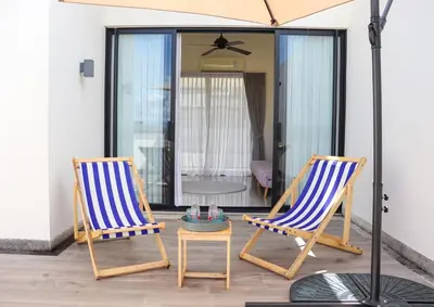 two chairs sitting on a patio with an umbrella at Lovely Townhouse in Laguna Park in Thalang