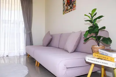 a purple couch in a living room with a potted plant at Lovely Townhouse in Laguna Park in Thalang