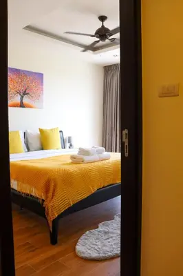 a bedroom with a bed with yellow sheets and a ceiling at Lovely Townhouse in Laguna Park in Thalang