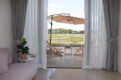 a room with a balcony with an umbrella and chairs at Lovely Townhouse in Laguna Park in Thalang