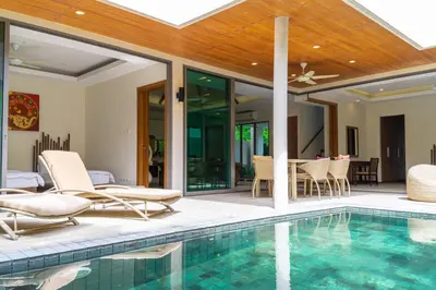 an indoor swimming pool with chairs and a house at Beautiful Pool Villa near Rawai Beach in Rawai Beach