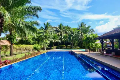 a swimming pool in a resort with palm trees at 3BR Casa Oasis - Beachfront Home in Laguna & Layan Chom Tawan and Maan Tawan Residences in Phuket Town