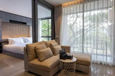 a bedroom with a couch and a bed and a window at Luxury Resort City Gate Kamala C33 in Kamala Beach