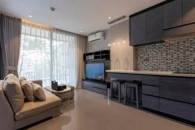 a living room with a couch and a kitchen with a tv at Luxury Resort City Gate Kamala C33 in Kamala Beach