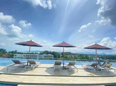 a group of chairs and umbrellas next to a pool at Aristo Resort Surin Beach M06 in Phuket Town