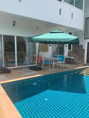 a swimming pool with an umbrella and chairs and a table with a table at Villa du Bonheur Mer et Nature Rawai beach in Phuket Town