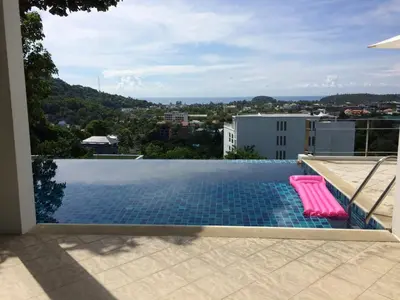 a swimming pool with two pink chairs on a roof at Villa Ginborn 5 bedroom Pool Villa with Sea View in Kata Beach in Kata Beach