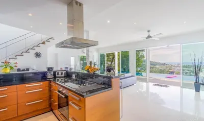 a kitchen with a stove top oven in a room with windows at Villa Ginborn 5 bedroom Pool Villa with Sea View in Kata Beach in Kata Beach