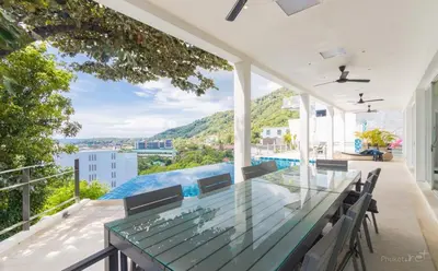 a patio with a glass table and chairs on a balcony at Villa Ginborn 5 bedroom Pool Villa with Sea View in Kata Beach in Kata Beach