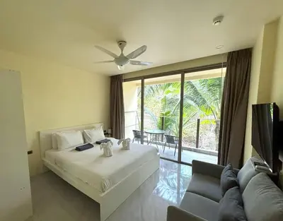 a bedroom with a bed and a couch and a large window at Great value! Convenient studio near Kamala beach in Kamala Beach