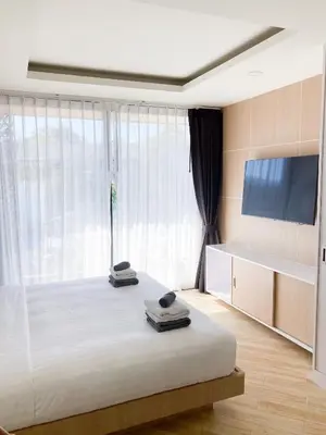 a bedroom with a large bed with a large window at Appartements avec piscine in Rawai Beach