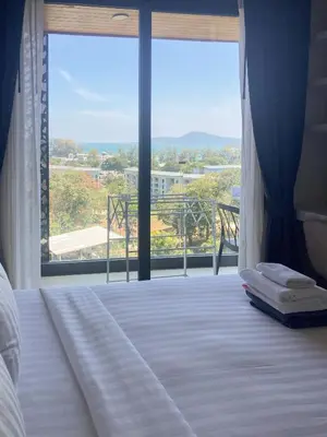 a bedroom with a bed and a large window at Appartements avec piscine in Rawai Beach