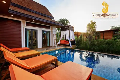 a swimming pool with orange furniture next to a house at Viangviman Luxury Resort, Krabi in Ao Nang Beach