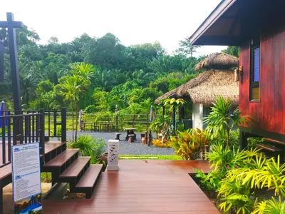 a wooden walkway leading to a house with a thatch roof at Baan Koh Kwang Pool Villa Krabi in Krabi town