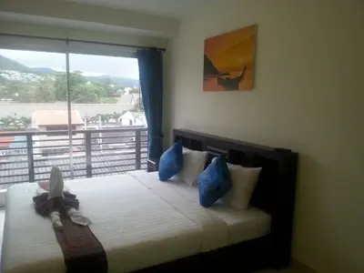 a bedroom with a bed with blue pillows and a window at The Green House in Kata Beach