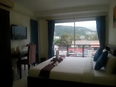 a bedroom with a bed and a large window at The Green House in Kata Beach