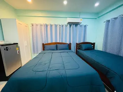 a bedroom with two beds with blue sheets and curtains at NUN GUEST HOUSE in Ban Bo Han