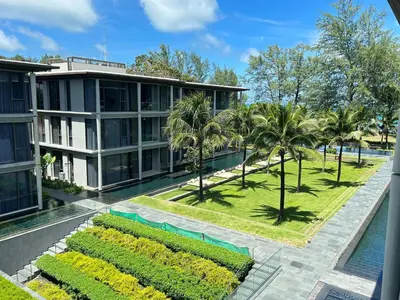 an aerial view of a building with a pool and palm trees at 2 Bedroom Beachfront Apartment With Sea Views in Mai Khao Beach