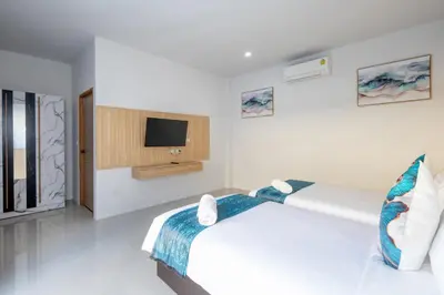a white bedroom with a bed and a tv at Sasi Pool Villa Phuket in Rawai Beach