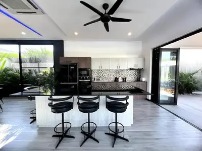 a kitchen with a ceiling fan and a counter with stools at Villa Christal - Modern 3 bedrooms with pool in Ban Saiyuan (1)