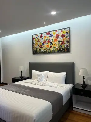 a bedroom with a bed with a painting on the wall at MYP Cherngtalay in Phuket Town