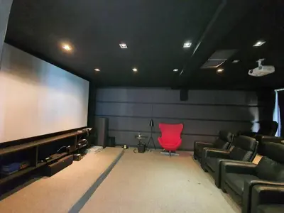 a cinema room with a red chair and a large screen at Villa Amonteera in Surin Beach
