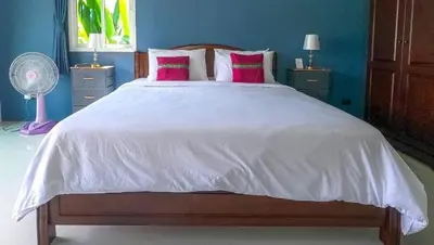 a bedroom with a large white bed with pink pillows at Lay Back Villa C2 with Kitchen & High speed Internet in Krabi town