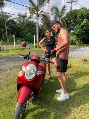 a man and a woman standing next to a red motorcycle at Lay Back Villa C2 with Kitchen & High speed Internet in Krabi town