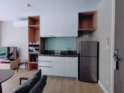 a kitchen with white cabinets and a black refrigerator at 1 Bedroom Pool view at Diamond Condo, Bangtao in Bang Tao Beach