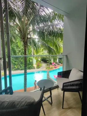 a living room with a palm tree and a pool at 1 Bedroom Pool view at Diamond Condo, Bangtao in Bang Tao Beach