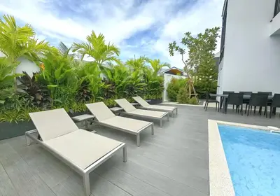 a row of white lounge chairs next to a swimming pool at Bangtao Luxury Pool Villa - Prymana in Phuket Town