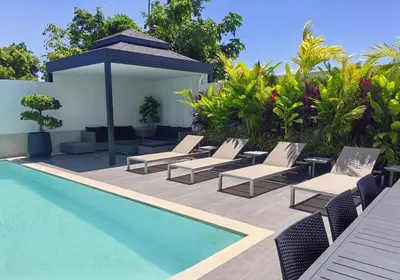 a swimming pool with lounge chairs and a umbrella next to a pool at Bangtao Luxury Pool Villa - Prymana in Phuket Town