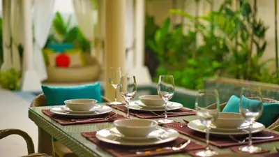 a table with plates and wine glasses on it at 4 Bedrooms Private Pool Villa near Rawai Beach in Rawai Beach