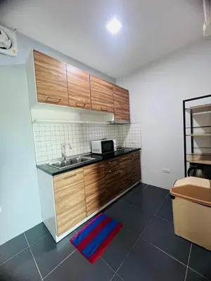 a kitchen with wooden cabinets and a sink at Arin Townhome @Bangtao in Ban Thalat Choeng Thale