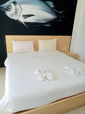 a bed with white sheets and two flowers on it at XX GO INN Aonang Beach โกอินน์ หาดอ่าวนาง in Ban Khlong Haeng