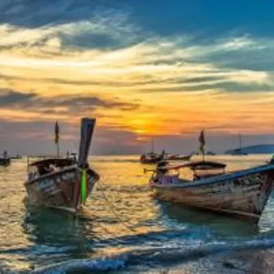 two boats sitting in the water at sunset at XX GO INN Aonang Beach โกอินน์ หาดอ่าวนาง in Ban Khlong Haeng
