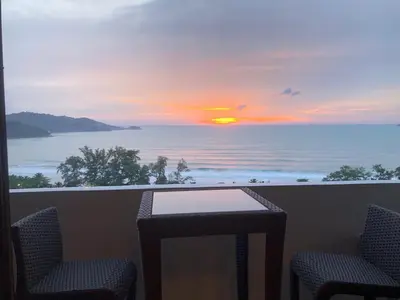 a view of a sunset from a balcony with chairs and a table at PATONG TOWER SEA FACING HIGH FLOOR New Bathroom in Patong Beach