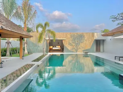 a swimming pool in front of a house at New luxury villa with maid Anchan Tropicana in Bang Tao Beach