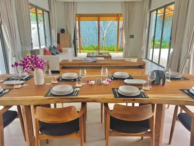 a dining room with a large wooden table and chairs at New luxury villa with maid Anchan Tropicana in Bang Tao Beach