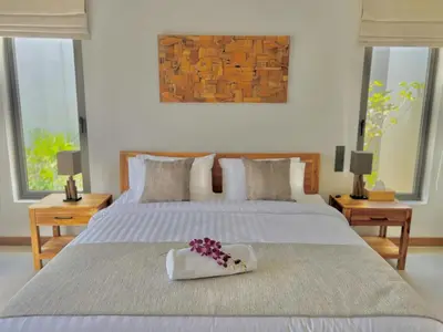 a bedroom with a bed with a bouquet of flowers on it at New luxury villa with maid Anchan Tropicana in Bang Tao Beach