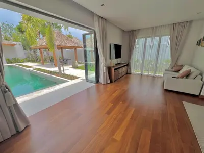 a living room with a couch and a television at New luxury villa with maid Anchan Tropicana in Bang Tao Beach
