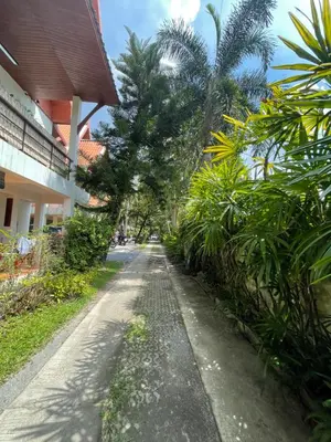 a dirt road in front of a building with palm trees at Aisawan Resort villa in Surin Beach