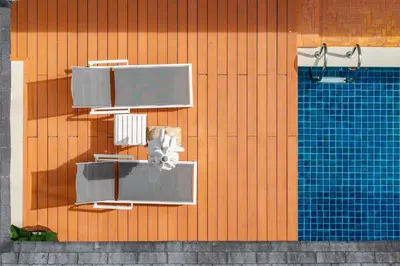a building with a pool and chairs and a swimming pool at Rosemary Villa 4 bedrooms with Pool near BangTao Beach in Bang Tao Beach