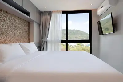 a bedroom with a large white bed and a window at Tropics Kamala Hill View Suite CTG D707, near Beach and Fantasea in Kamala Beach