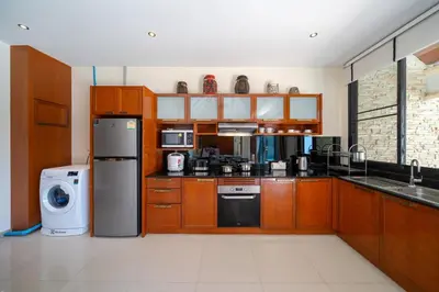 a large kitchen with wooden cabinets and appliances at Private 2BR Pool Villa 2D03 in Gated Residence Rawai VIP Villas in Rawai Beach