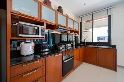 a kitchen with wooden cabinets and black counter tops at Private 2BR Pool Villa 2D03 in Gated Residence Rawai VIP Villas in Rawai Beach