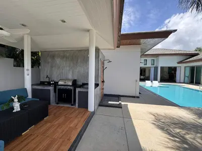 an outdoor patio with a kitchen and a swimming pool at Pool Villa - 3 Bedroom- Walking to Bangtao Beach, Restaurants and Supermarkets in Bang Tao Beach